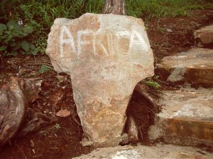 Stein mit den ungefähren Umrissen von Afrika, draufgekratzt steht Africa
